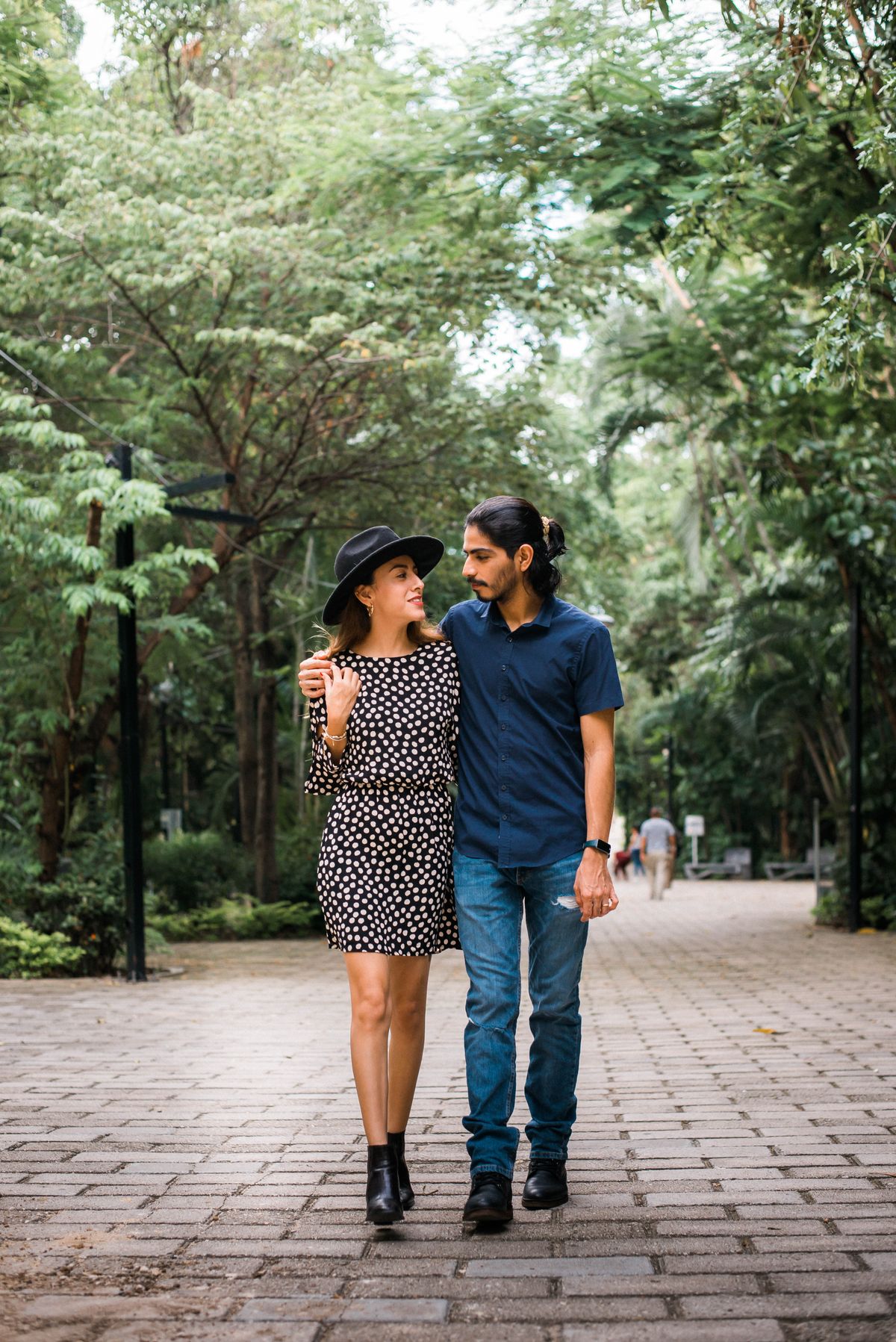 A couple walking together through a leafy park