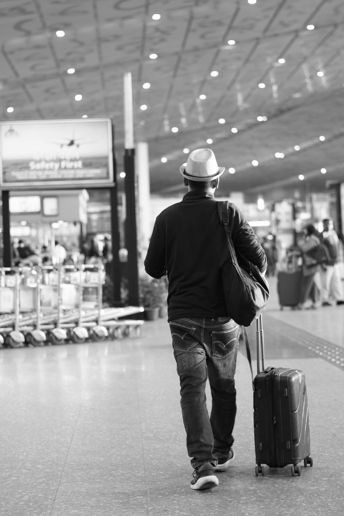 A traveler walking through an airport terminal with luggage